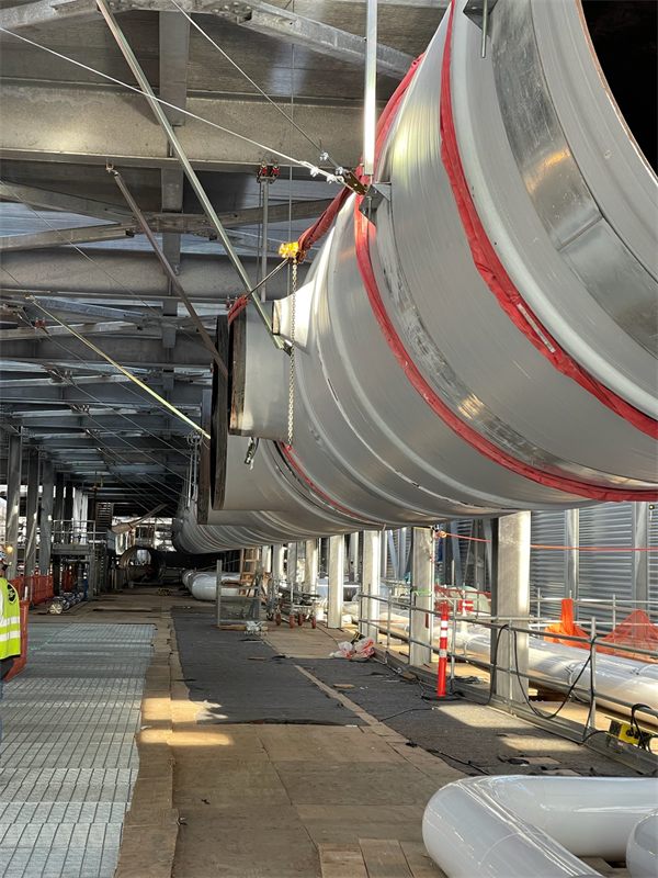 Large round exhaust duct hung overhead inside a building under construction