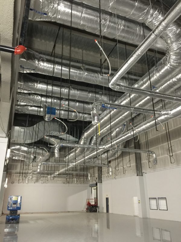 Insulated round duct runs hung from the ceiling of a large open room