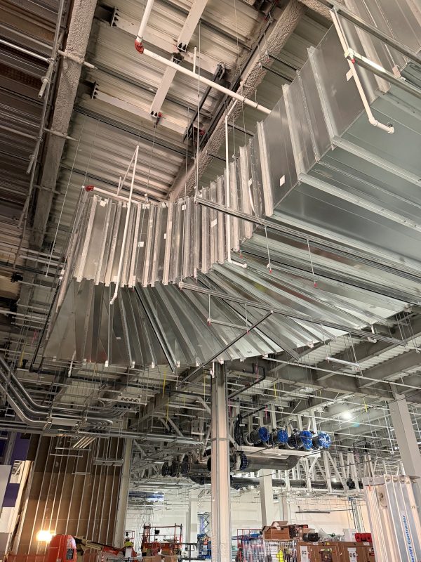 Large galvanized rectangular duct and elbow hung from a steel deck