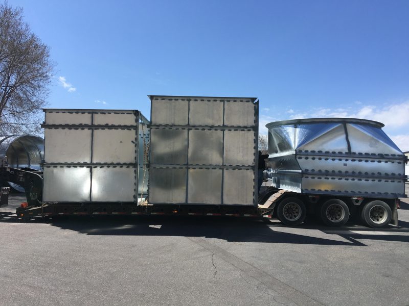Large galvanized rectangular plenums and a transition loaded on a lowboy trailer